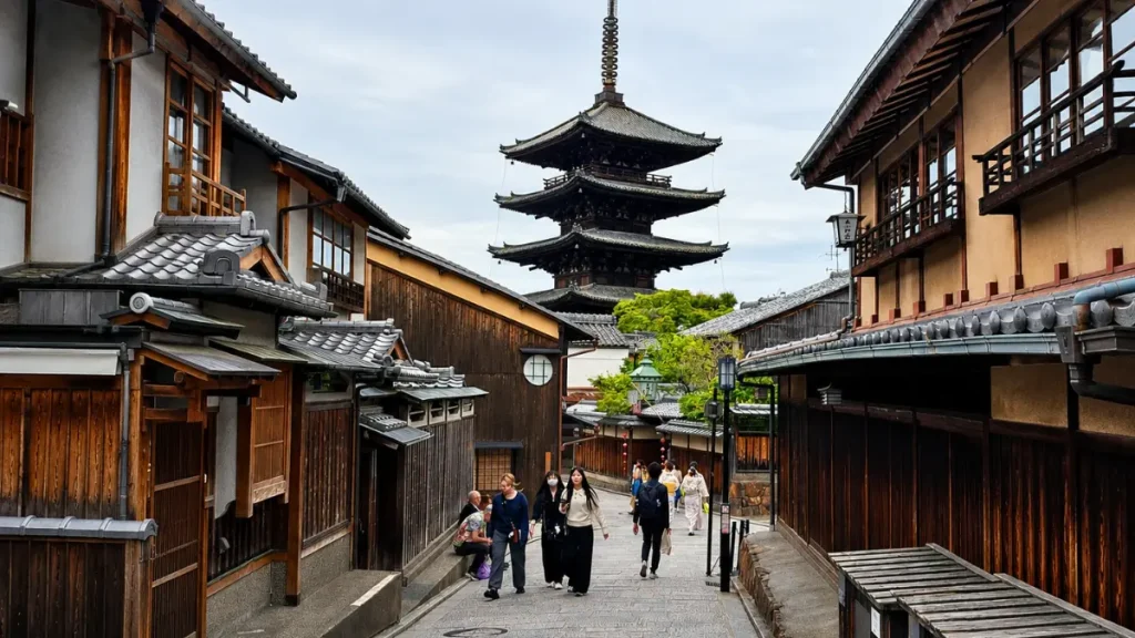 Rues historiques de Kyoto : voyage dans le temps au cœur du Japon Rue pavée de Kyoto bordée de maisons en bois traditionnelles et de lanternes, illustrant l'atmosphère authentique de la ville.