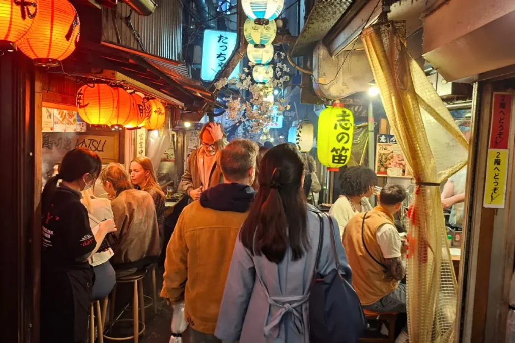 L'ambiance vibrante des rues japonaises : entre tradition et modernité Rue animée au Japon avec des lanternes rouges, des enseignes colorées et des passants, illustrant la vie quotidienne et l'énergie du pays.
