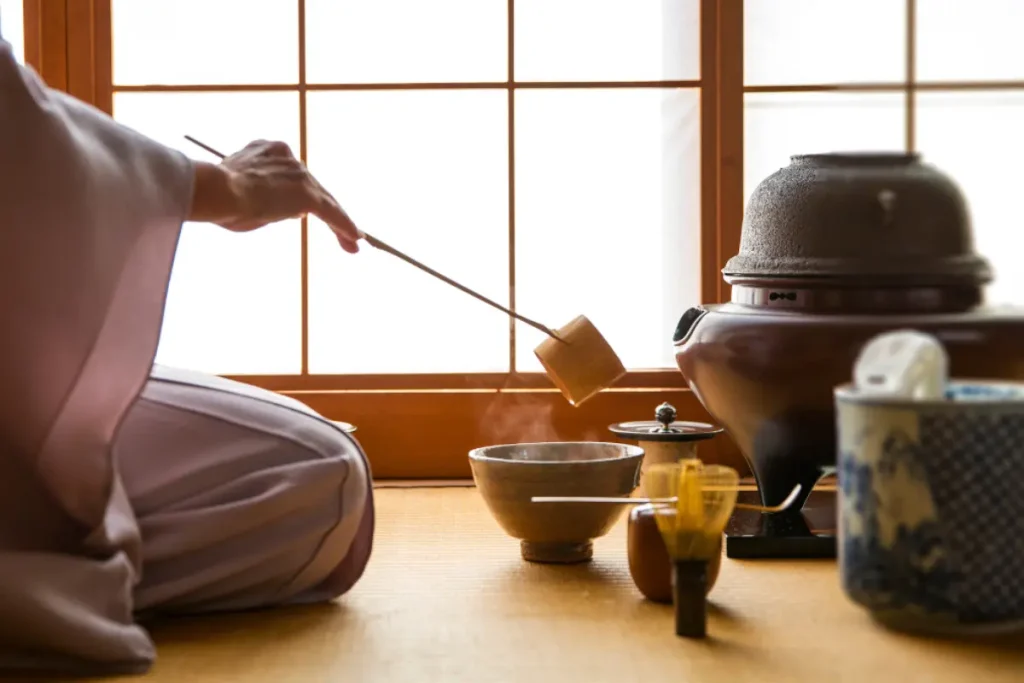 Découvrir la cérémonie du thé : une expérience culturelle unique au Japon Femme en kimono préparant une cérémonie du thé dans une pièce traditionnelle, symbole de l'art et de la culture japonaise.