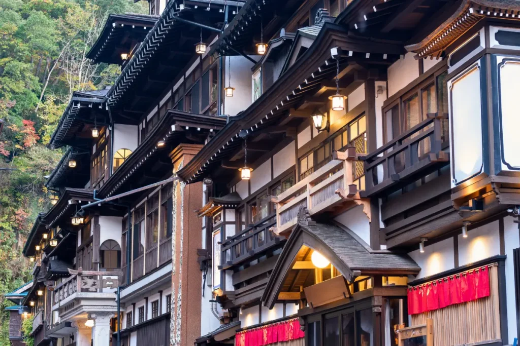 Ryokan traditionnel : l'hébergement authentique pour une immersion au Japon Ryokan japonais en bois avec lanternes rouges, niché dans un cadre naturel, offrant une expérience d'hébergement traditionnelle et apaisante.