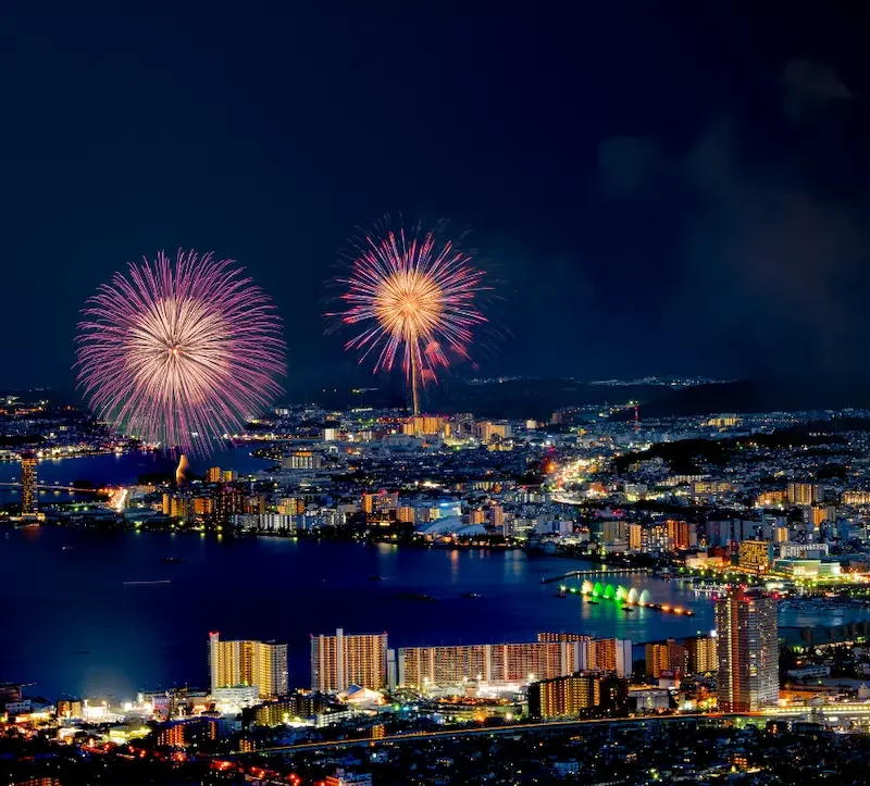 Vue nocturne d'une baie du lac Biwa ville illuminée de nuit au bord d'un lac avec feux d'artifice