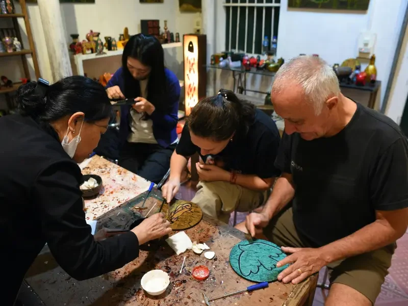 Expérience artisanale au Japon – Initiez-vous aux techniques traditionnelles Voyageurs participant à un atelier artisanal traditionnel japonais avec un artisan