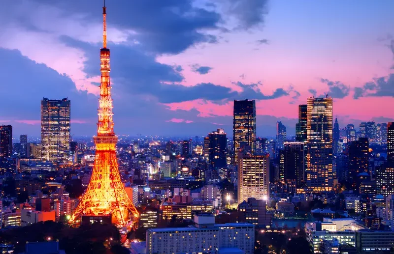 Voyage Japon 15 jours – Itinéraire Sakura | J'Go Japon Vue nocturne de la tour de Tokio illuminée, entourée de gratte-ciel.