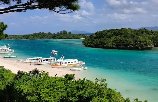 Baie aux eaux turquoise avec plages, îlots boisés et bateaux à Ishigaki.