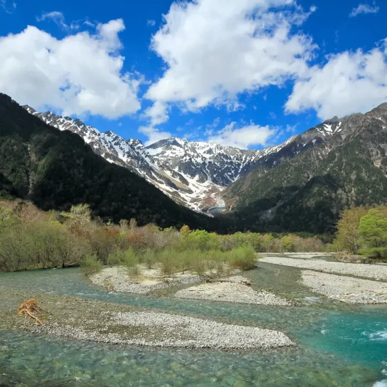 Les Alpes Japonaises : Kamikochi au Japon paysage montagneux des alpes japonaises entouré de fôret et d'un ruisseau bleu turquoise