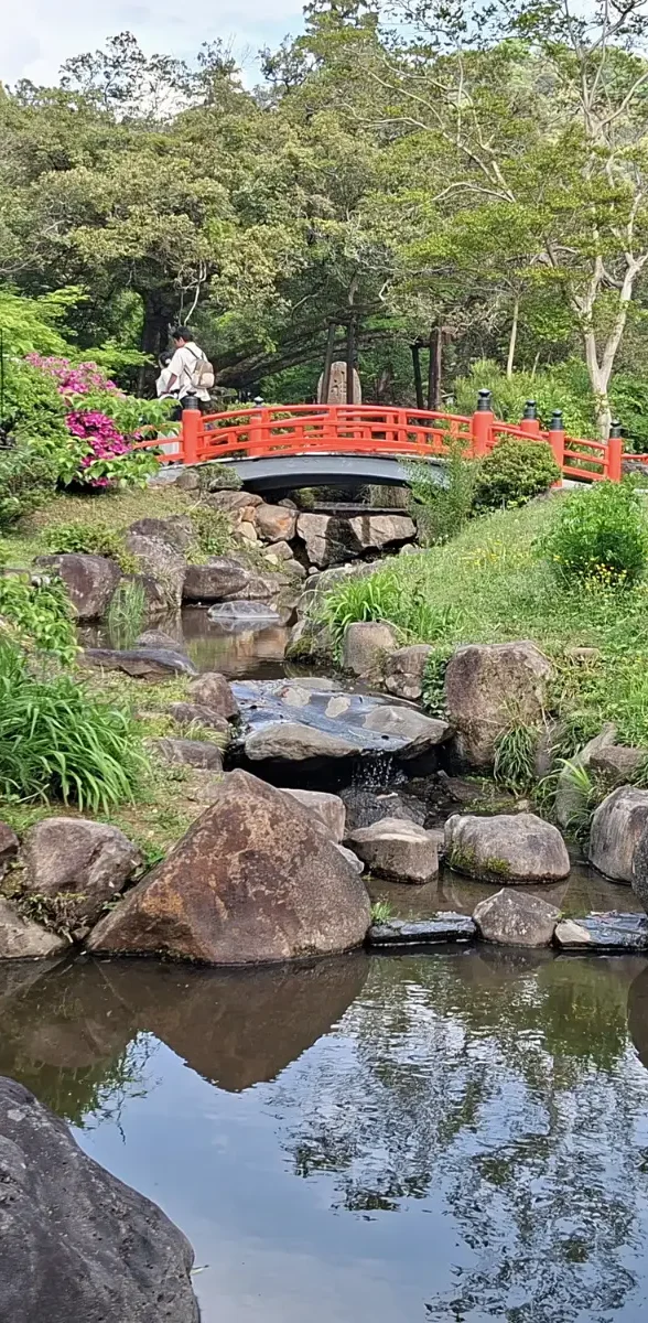 Jardin japonais traditionnel à Nara au Japon Petit pont rouge dans un jardin japonais traditionnel à Nara au Japon, entouré de végétation, pierres et bassin paisible.