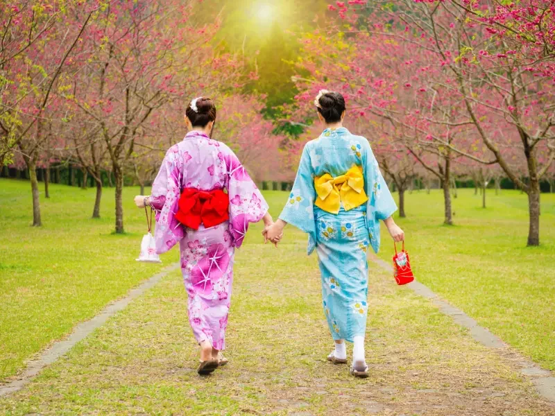 Expérience kimono au Japon – Immersion culturelle et souvenirs uniques à Kyoto Deux femmes en kimono traditionnel marchant dans un jardin au Japon lors d’une expérience culturelle à Kyoto