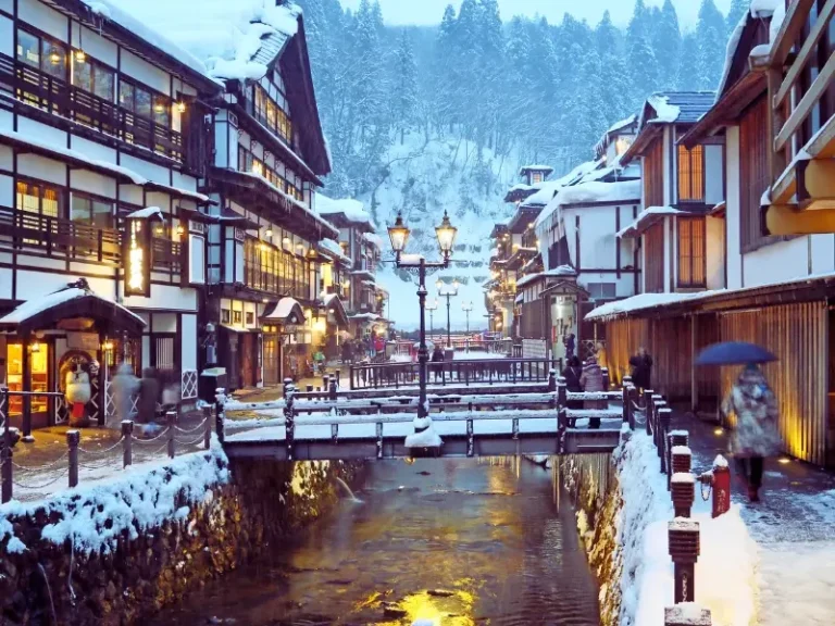Village japonais enneigé avec ryokan et onsen au bord d’une rivière en hiver au Japon