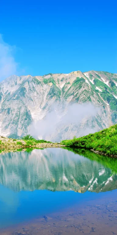 Pack Ajisai Lac de montagne aux eaux calmes reflétant les Alpes japonaises sous un ciel bleu, illustrant le Pack Ajisai au Japon.