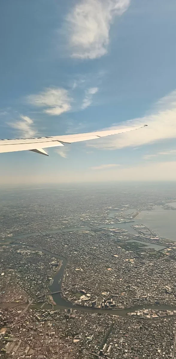 Vue aérienne de Tokyo depuis un avion au Japon Vue aérienne de Tokyo depuis un avion à l’arrivée au Japon, avec l’aile de l’appareil au-dessus de la baie et de l’immense paysage urbain.