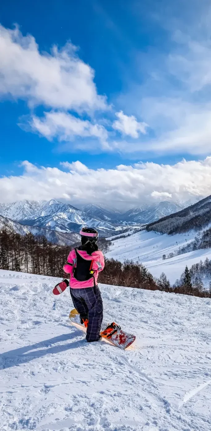 Personne pratiquant le snowboard dans une station de ski à Niigata avec montagnes enneigées