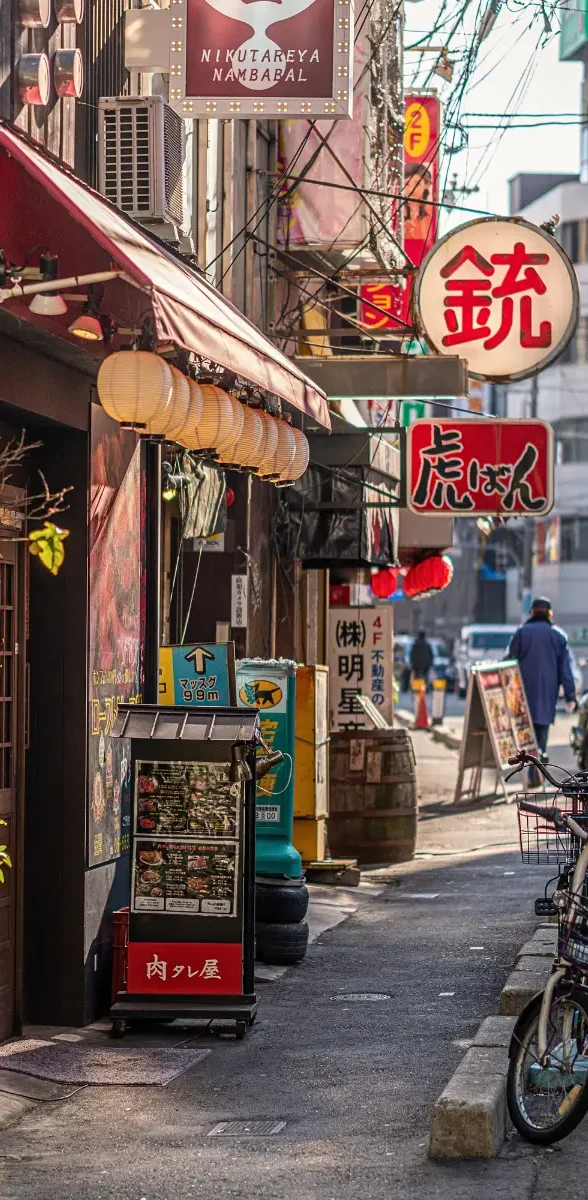 Ruelle animée de Dotonbori et petits restaurants traditionnels à Osaka Petite rue commerçante de Dotonbori à Osaka avec lanternes japonaises, enseignes lumineuses et restaurants traditionnels
