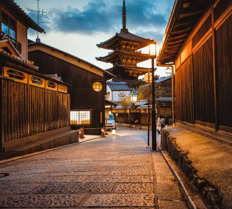 Rue traditionnelle de Kyoto avec pagode au coucher du soleil Rue pavée traditionnelle de Kyoto avec maisons en bois et pagode japonaise éclairée au coucher du soleil