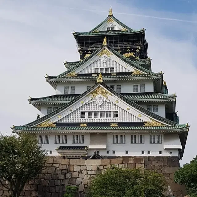 Osaka entre street food & quartiers animés | Voyage Japon | J’Go Japon Château d’Osaka emblématique entouré de nature dans la ville d’Osaka au Japon