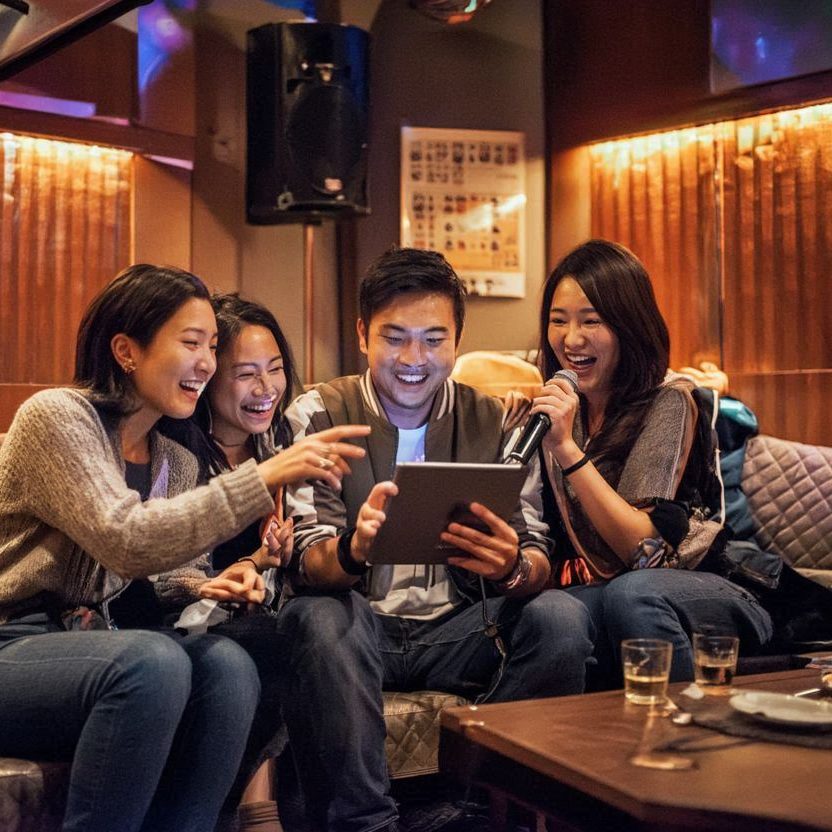 Groupe d’amis chantant dans un karaoké japonais dans une salle privée