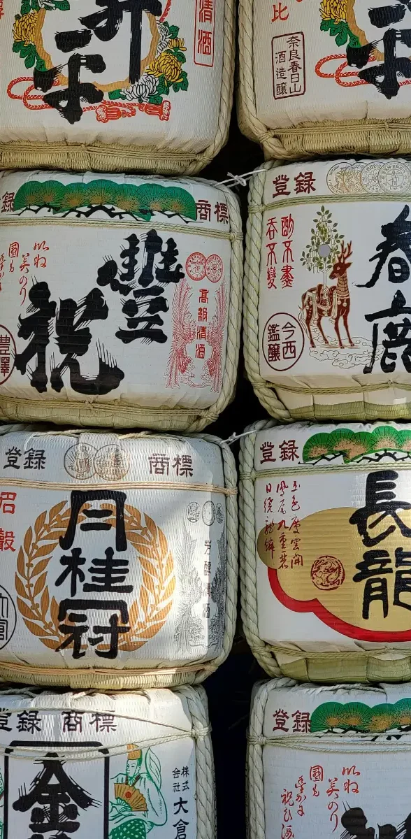 Empilement de barils de saké japonais décorés de calligraphies traditionnelles, représentant le savoir-faire brassicole de Hyogo