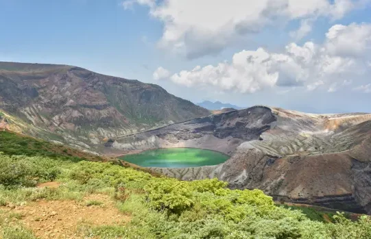 Lac de cratère Okama entouré des reliefs volcaniques du mont Zaō.