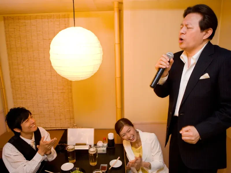 Homme chantant au karaoké dans un restaurant japonais avec des amis