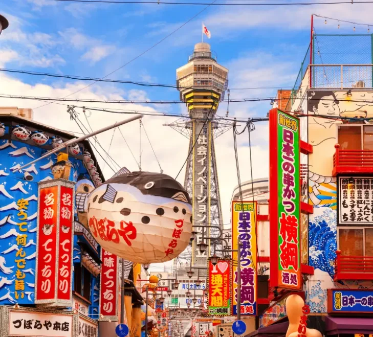 Rue animée de Shinsekai avec enseignes colorées et tour Tsūtenkaku à Osaka.