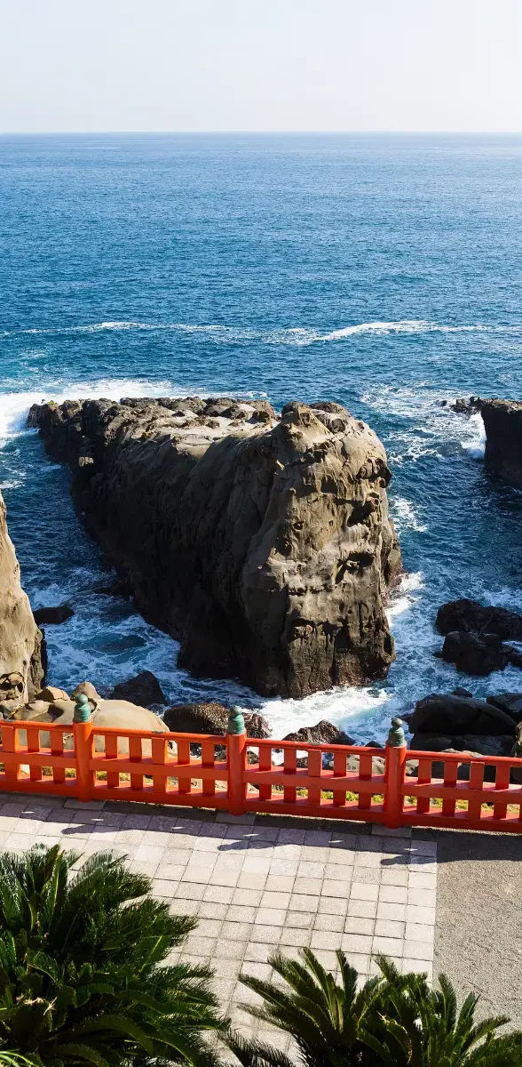 Côte sauvage d’Aoshima et formations rocheuses à Miyazaki Vue sur les formations rocheuses côtières d’Aoshima à Miyazaki, bordées par l’océan Pacifique et un pont rouge.