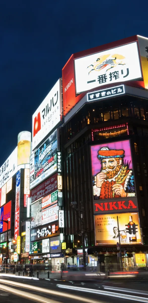 Quartier Susukino à Sapporo avec enseignes lumineuses de nuit Quartier animé de Susukino à Sapporo avec panneaux lumineux et circulation de nuit