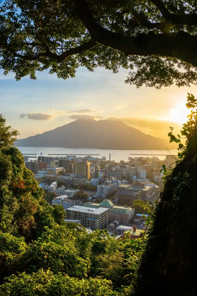 Kagoshima Vue sur le volcan Sakurajima au coucher du soleil depuis Kagoshima au Japon, entre nature luxuriante, ville japonaise et baie de Kagoshima.