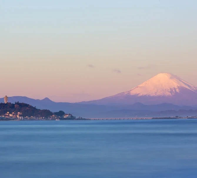 Vue sur Enoshima et le mont Fuji au-delà de la baie au coucher du soleil.