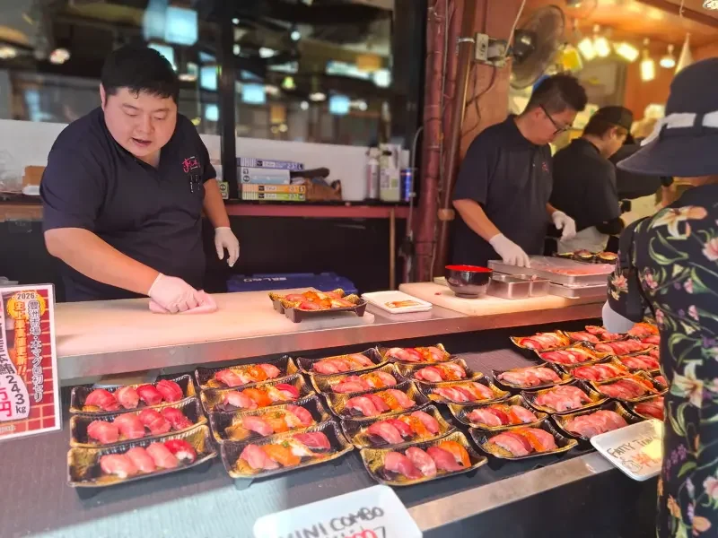 Stand de sushi dans un marché japonais Préparation de sushis frais dans un marché japonais animé.