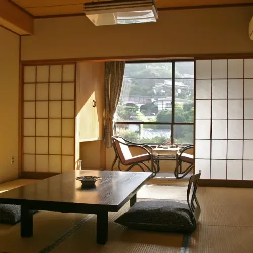 Intérieur d'un ryokan japonais avec tatamis, portes coulissantes shoji et vue sur un jardin