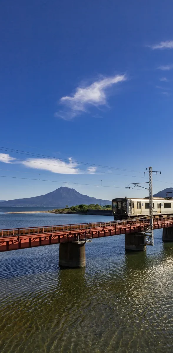 Train traversant un pont avec vue sur le volcan Sakurajima à Kagoshima au Japon