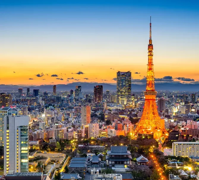Vue sur Tokyo au coucher du soleil avec la tour de Tokyo illuminée au premier plan.