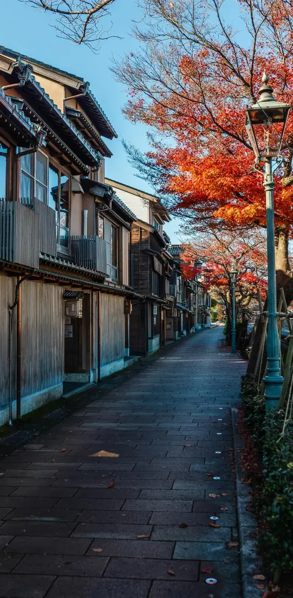Ruelle traditionnelle de Kanazawa en automne à Ishikawa au Japon Rue traditionnelle du quartier historique de Kanazawa à Ishikawa au Japon, bordée de maisons en bois et d’érables rouges.