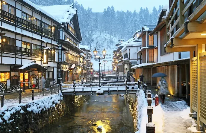 Ruelles et auberges traditionnelles de Ginzan Onsen illuminées sous la neige.