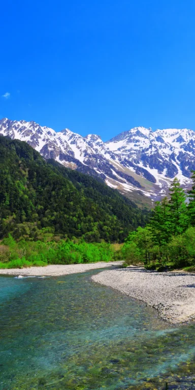 Pack Kikyo Rivière de montagne entourée des Alpes japonaises enneigées sous un ciel bleu, illustrant le Pack Kikyo au Japon.